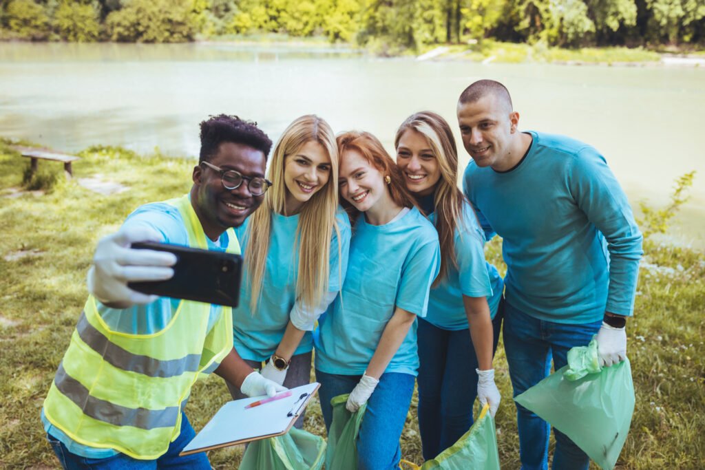 young african man takes a selfie with a group of friends who are participating in a community cleanup event.